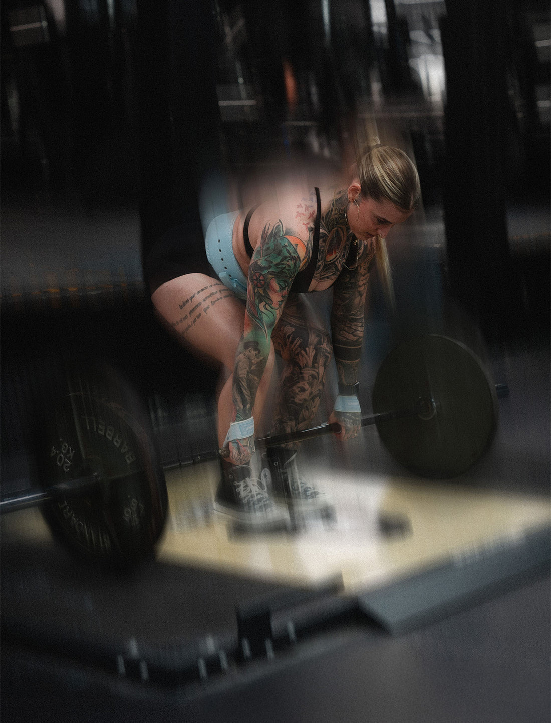 woman doing romanian deadlift wearing uppper lifting straps and lever belt